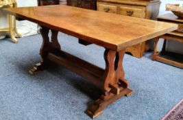 An English oak and elm trestle dining table, well figured top, pierced supports, twin central