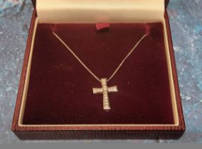 A 9ct white gold cross, channel set with fifteen diamonds, surmounted with a central claw set