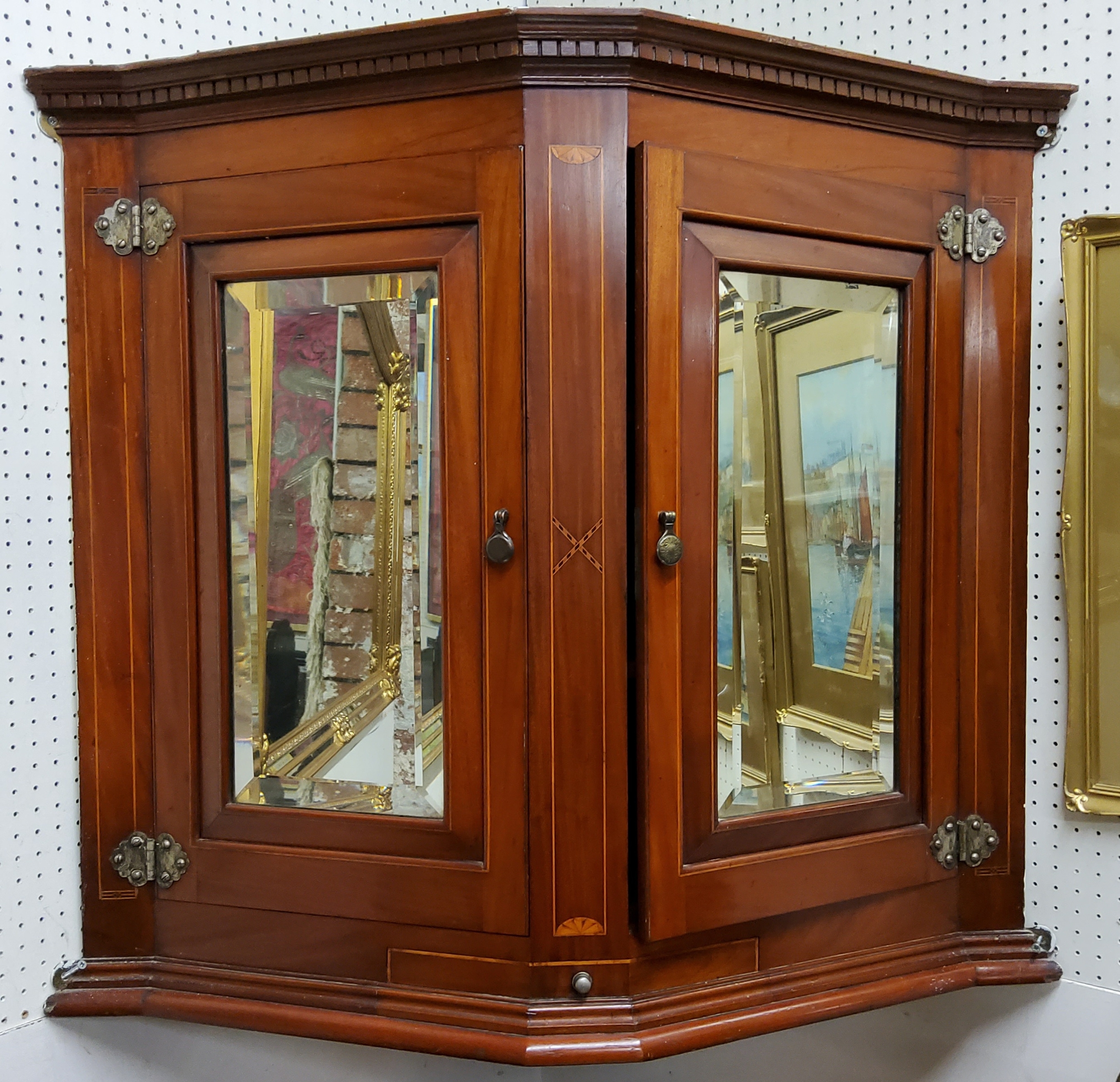 An Edwardian Sheraton Revival canted corner cupboard, dental cornice above mirror panelled doors