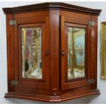 An Edwardian Sheraton Revival canted corner cupboard, dental cornice above mirror panelled doors