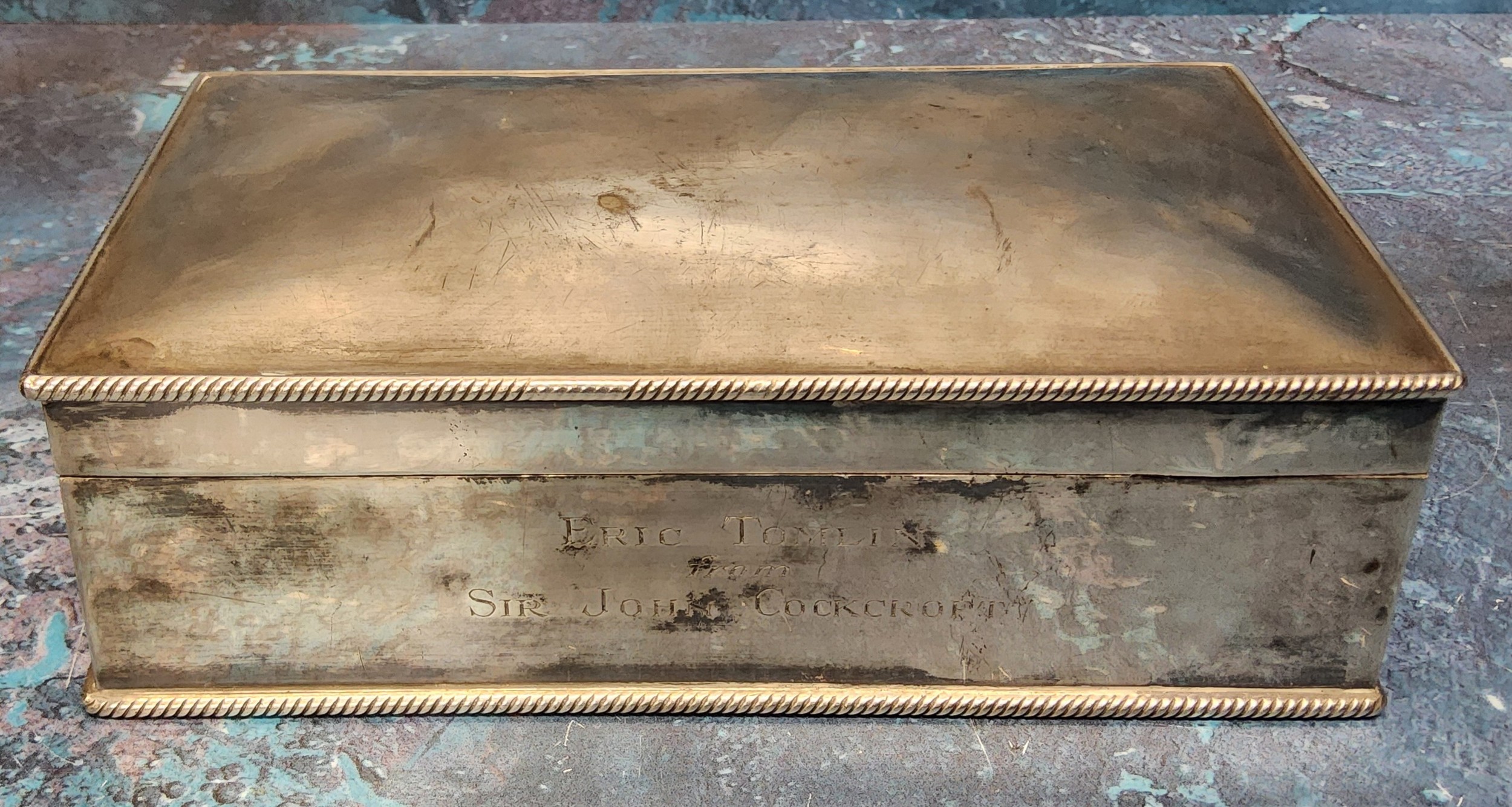 A silver plated cigarette box, cedar lined, engraved Eric Tomlin from Sir John Cockcroft (