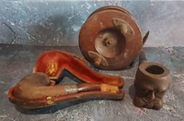 An early 20th century novelty pipe. carved with a face;  another, silver mounted;  a fishing reel (