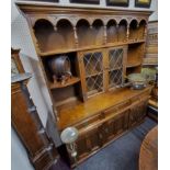 An Old Charm type oak Jacobean Revival kitchen dresser, oversailing ogee cornice above two astagal