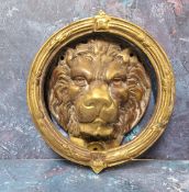 A large brass lion mask door knocker,  the mask within a reeded ring knocker cast with floral bosses