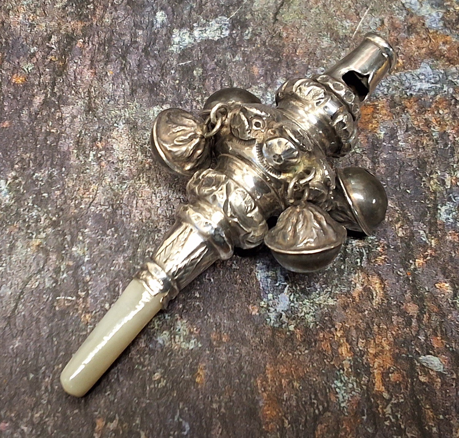 A 19th century silver child's rattle, chased with flowers and scrolling foliage, whistle terminal,