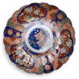 A Japanese Imari shaped circular charger, decorated with alternating panels of blossoming