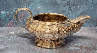 A George IV silver lobed ovoid milk jug, embossed with flowers and scrolls, bold spout, acanthus