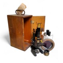 An American Bausch & Lomb brass and ebonized metal microscope, with three lenses, two Spencer,