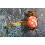 An Edwardian novelty tape measure, as an owl, 'marbled' pink body, 4.25cm high, c.1910