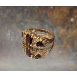 A 9ct gold garnet and diamond gypsy ring, the central oval garnet flanked by two round garnets