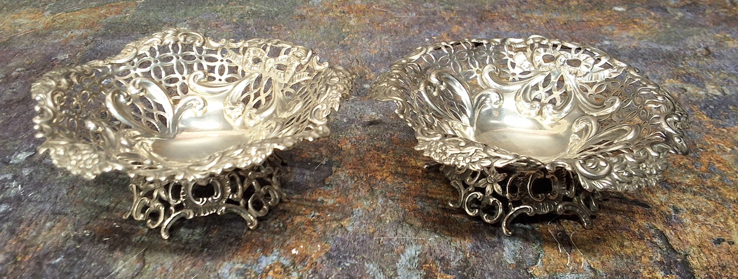 A pair of silver shaped circular sweetmeat dishes, embossed and pierced with ribbon tied swags,