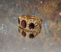 A 9ct gold, garnet and diamond gypsy ring, centrally set oval garnet flanked by a further two,