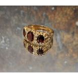 A 9ct gold, garnet and diamond gypsy ring, centrally set oval garnet flanked by a further two,