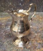 A George III silver pedestal cream jug, acanthus-capped scroll handle, shaped circular foot, stipple