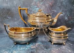 A silver composed three-piece boat shaped tea service, reeded band, gadrooned border, ball feet,