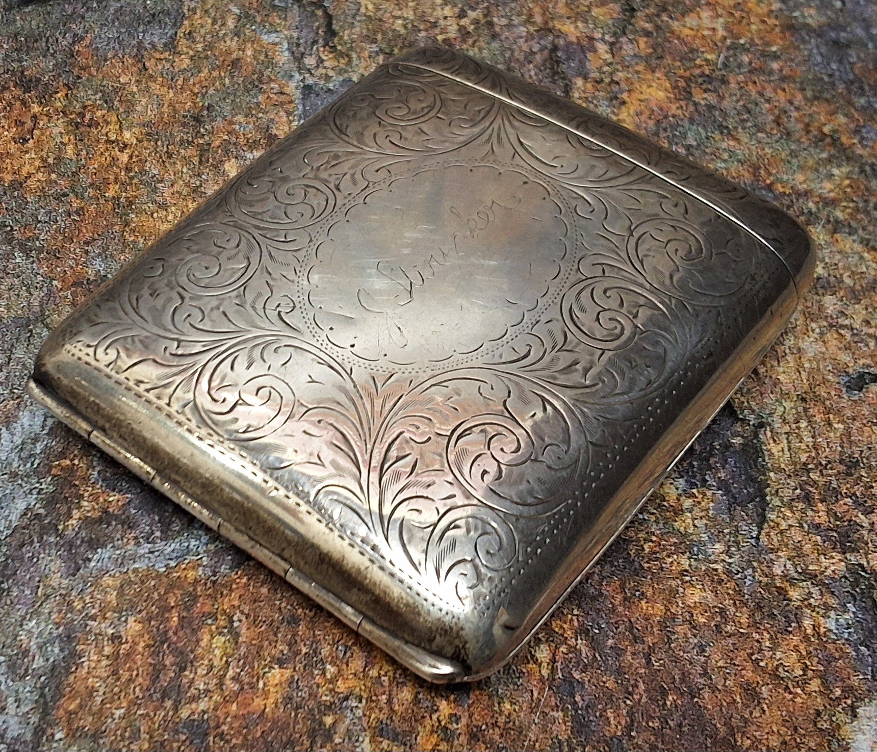 An unusual George V silver rounded rectangular cigarette case, hinged cover, engraved and chased