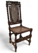 A Carolean carved walnut hall chair, 17th century, the caned back panel flanked by barley twist side