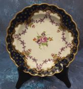 A Worcester shaped circular plate, painted with a central bouquet of flowers and purple swags the
