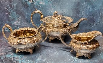 A George IV silver three piece compressed ovoid tea service, embossed with flowers and leafy