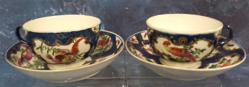 A pair of Worcester blue scale  teacups and saucers, painted with alternating cartouche and vase