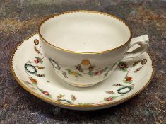 A Bristol ogee teacup and saucer, decorated in polychrome with wreath and foliate swags, gilt dentil