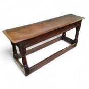 An early 17th century Charles I English oak bench or long joint stool, moulded top above a deep