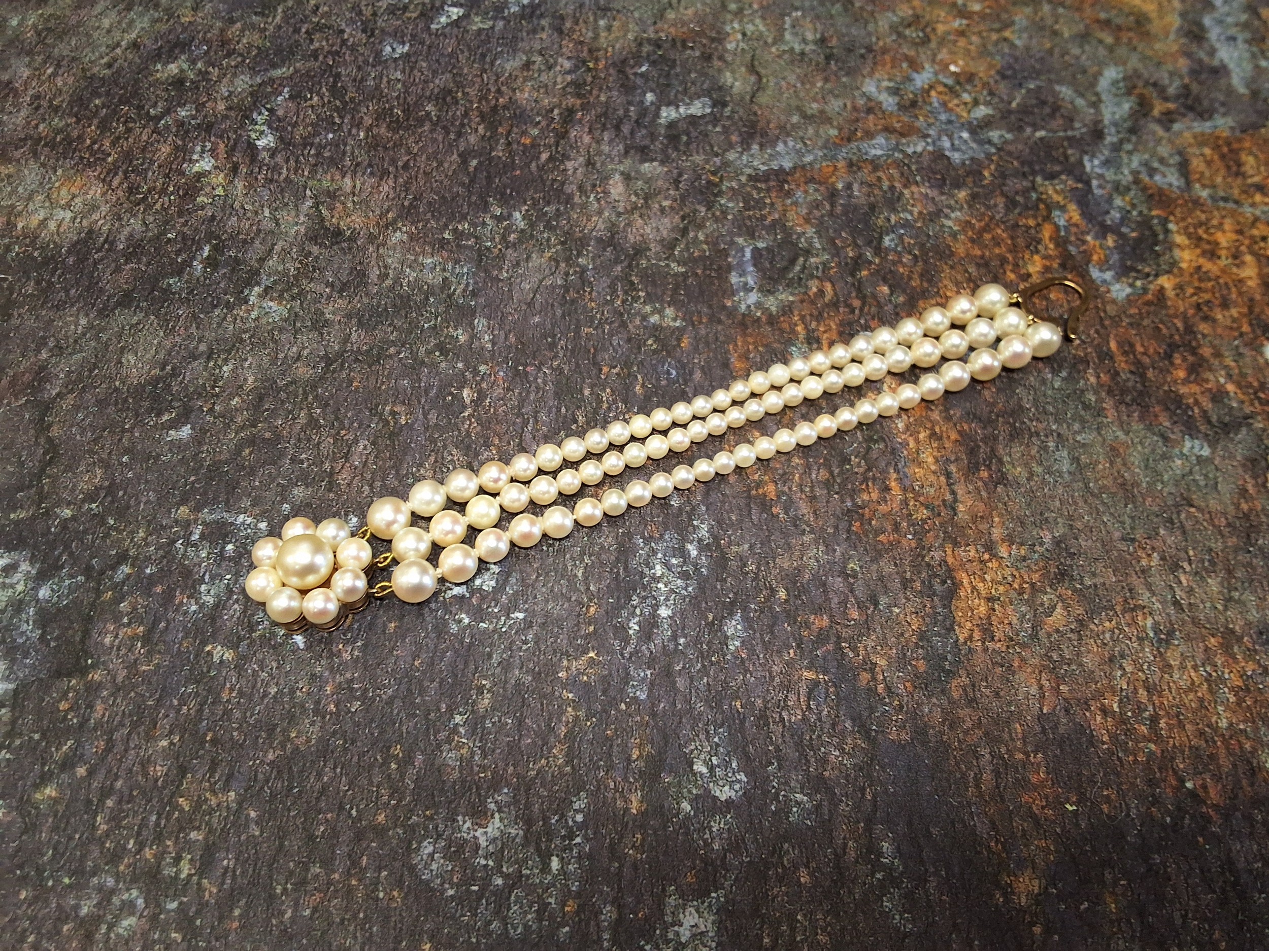 A 9ct gold three stand graduated pearl bracelet, the largest 6.9mm to 4.1mm, the 9ct gold clasp in