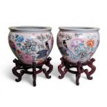 A pair of 20th century Chinese fish bowls on stands, decorated to the exterior with birds amongst