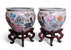 A pair of 20th century Chinese fish bowls on stands, decorated to the exterior with birds amongst