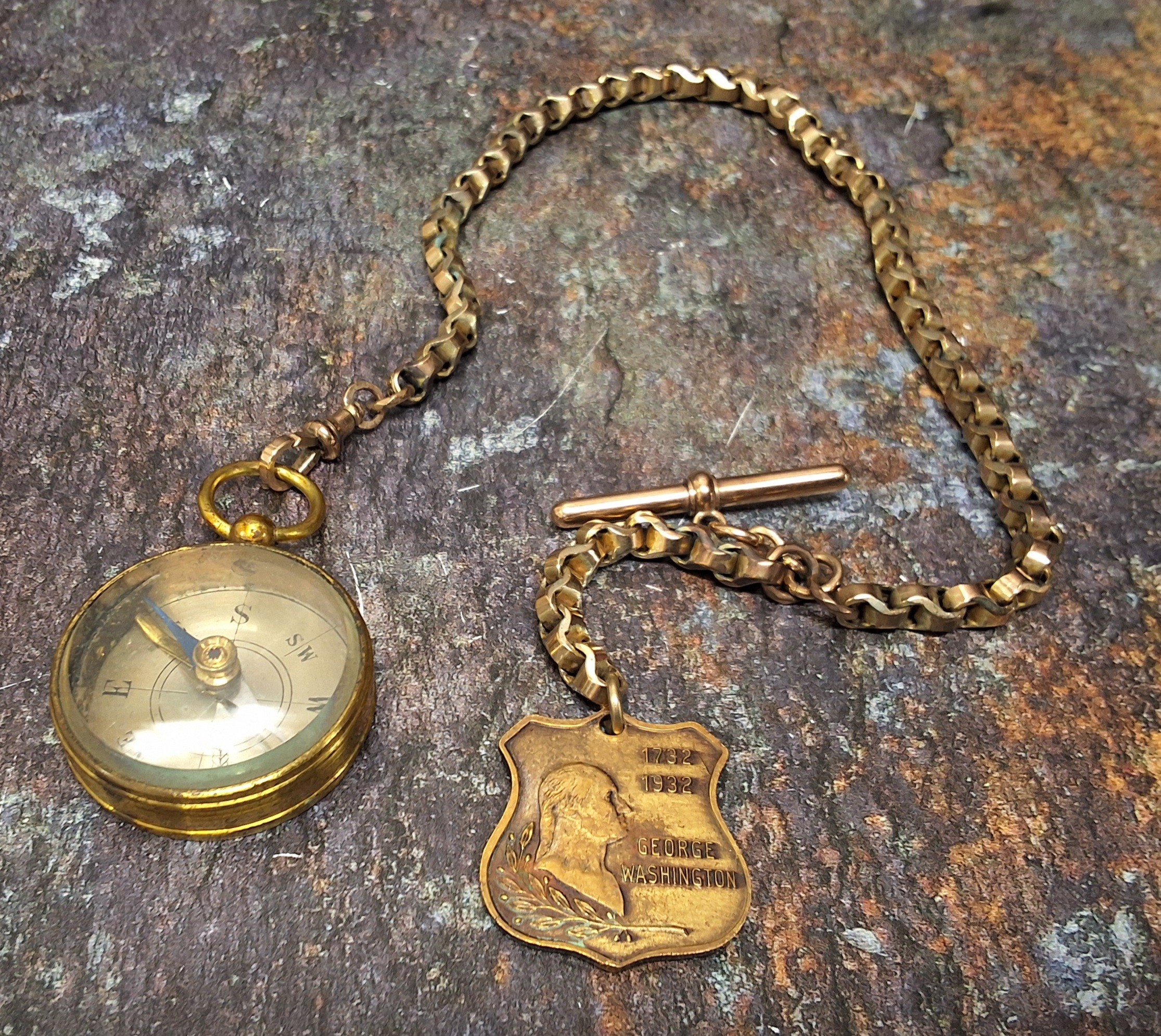 An early 20th century gilt metal compass, on gold plated Albert, George Washington shield shaped fob