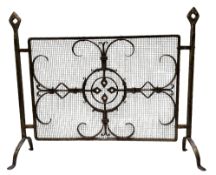 An early 20th century wrought iron fire guard with a mediaeval geometric design, bold openwork