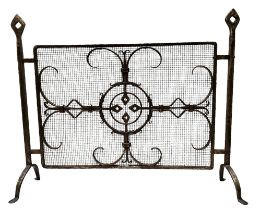 An early 20th century wrought iron fire guard with a mediaeval geometric design, bold openwork