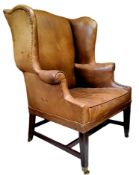A George III mahogany wingback armchair, c1780, in close nailed leather upholstery, seat height