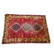 A 19th century Iranian hand woven rug, in rich tones of red and cream, central geometric guls,