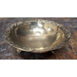 A South American silver coloured metal shaped circular bowl, ring loop handles, ball and claw