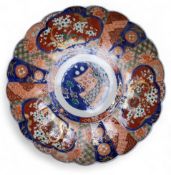 A Japanese Imari shaped circular charger, decorated with alternating panels of blossoming