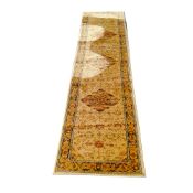 A 20th century Persian runner, machine made woolen pile in tones of gold, three central flower-