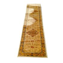 A 20th century Persian runner, machine made woolen pile in tones of gold, three central flower-