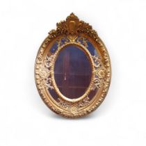A substantial gilt oval mirror, with shield anmd floral cresting 125cm high, 94cm wide