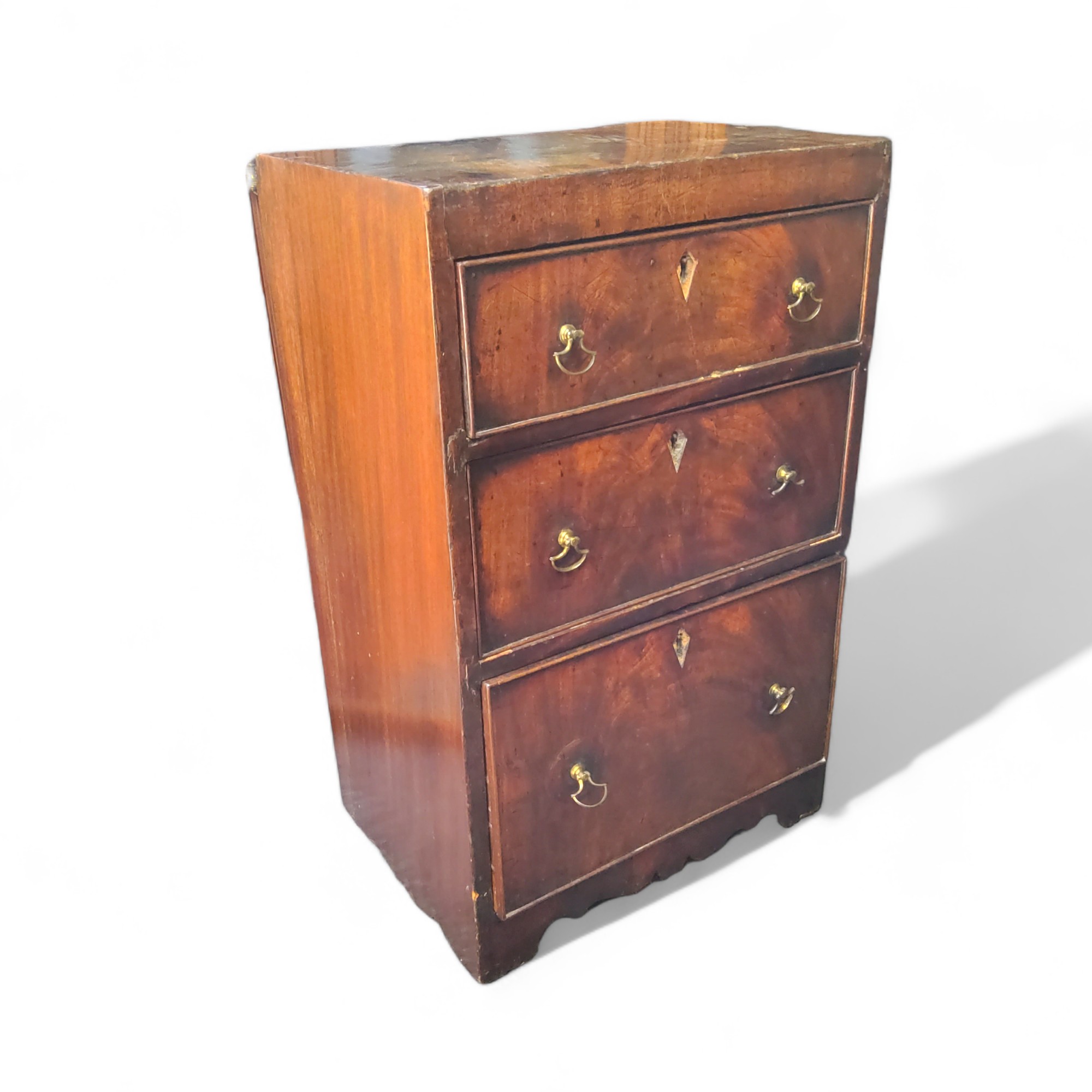 A small George III flamed mahogany chest of three graduated cockbeaded drawers, lozenges removed,
