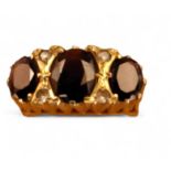 A 9ct gold ring, set with a central oval garnet, flanked by two smaller, interspersed with two white