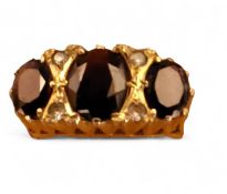 A 9ct gold ring, set with a central oval garnet, flanked by two smaller, interspersed with two white