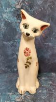 A C.H. Brannnam (Barnstaple) pottery cat,  seated, with head tilted, painted with stylised