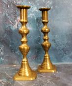 A pair of 19th century brass ejector candlesticks, reel sconces, canted bases, 25cm high, c.1820