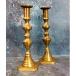 A pair of 19th century brass ejector candlesticks, reel sconces, canted bases, 25cm high, c.1820