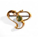 A 15ct gold Art Nouveau scroll brooch, set with an oval peridot and seed pearl, 3.4g