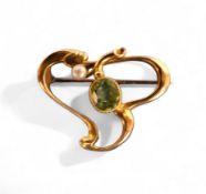 A 15ct gold Art Nouveau scroll brooch, set with an oval peridot and seed pearl, 3.4g