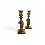 A pair of Regency bronzed figural candlesticks, detachable floral nozzles, spreading square bases,