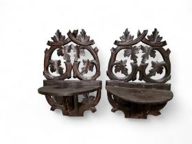 A pair of early 20th century Black Forest wall brackets, carved with scrolling leaves and foliage,