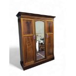 An Edwardian mahogany double wardrobe, upswept cornice, panelled doors with boxwood stringing,